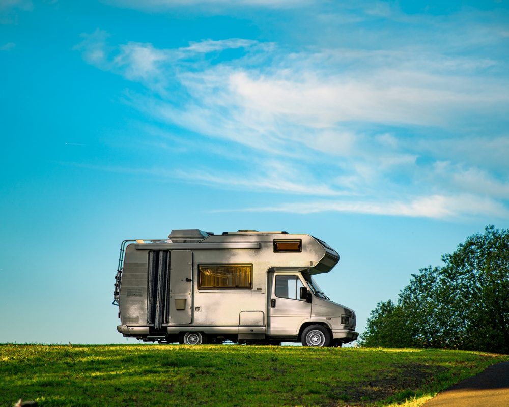 closeup-shot-of-a-camper-van-parked-in-the-green-field-under-the-blue-sky